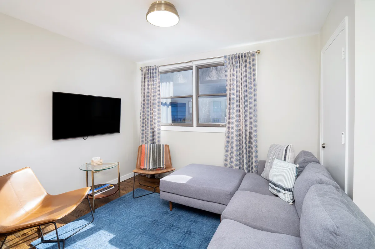 A cozy living room with a sofa, television, window, and inviting décor. Sunlight filters in, creating a bright and comfortable space perfect for relaxing or socializing after a day of adventure.