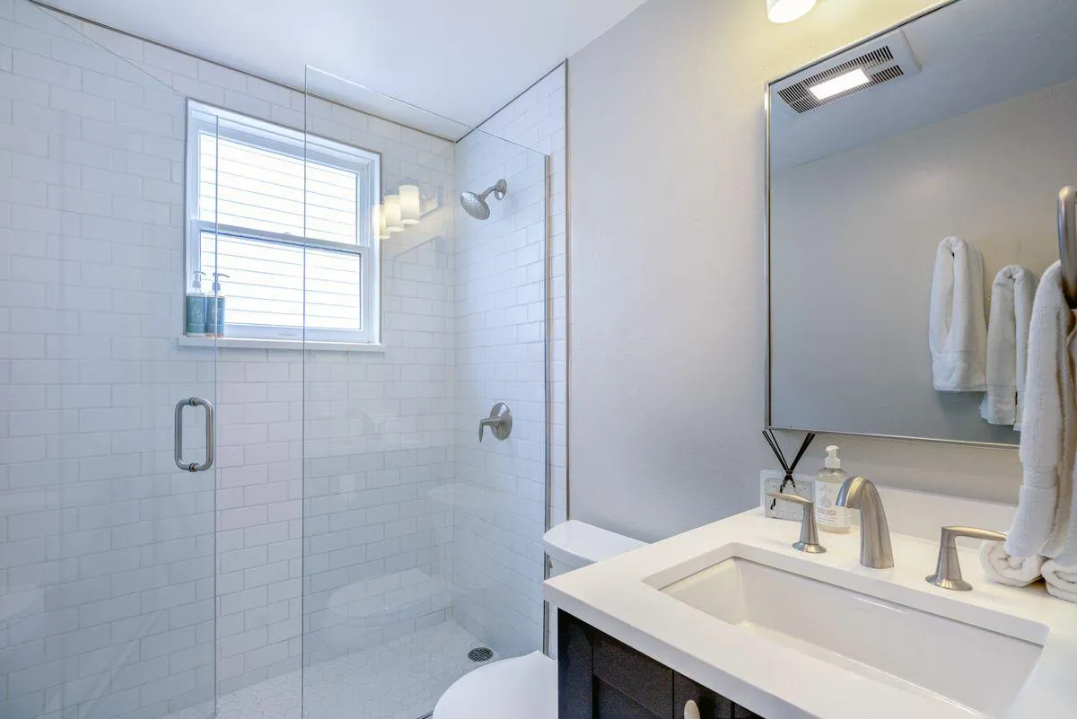 A modern bathroom featuring a glass shower enclosure, sleek sink and faucet, and a large mirror. The space feels fresh and newly renovated, with clean lines and a bright, calming ambiance.